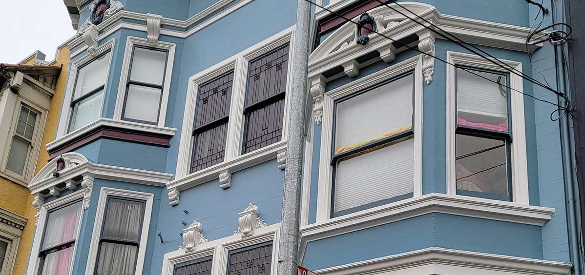 Close-up of windows on a blue building with ornate white trim.