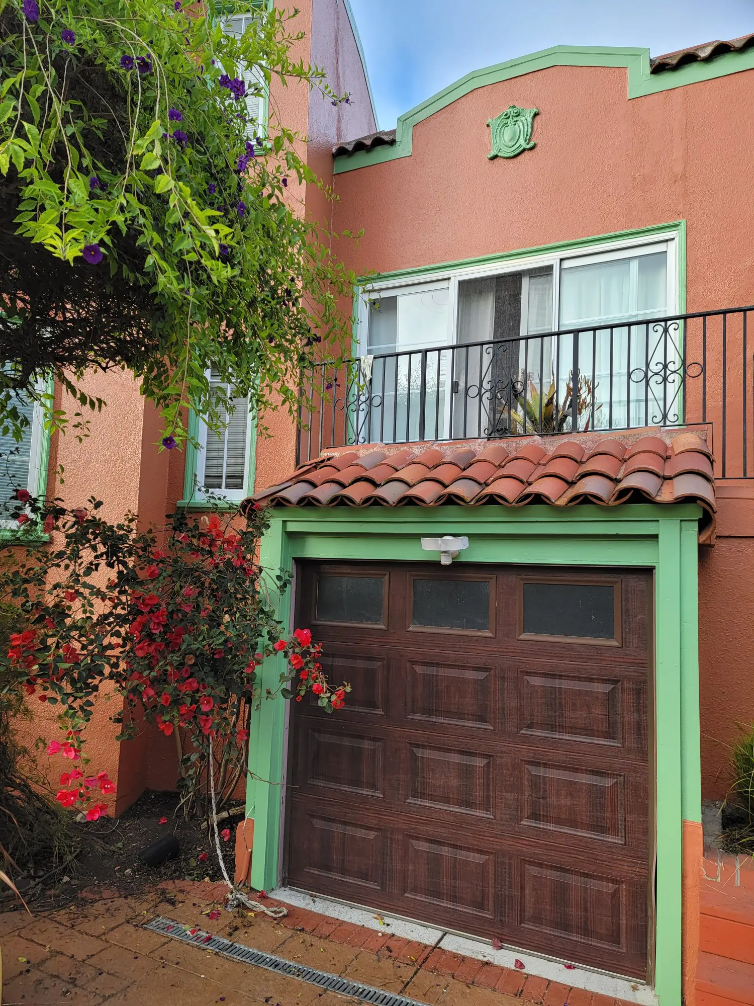 A brick house with a wooden garage door and balcony above.
