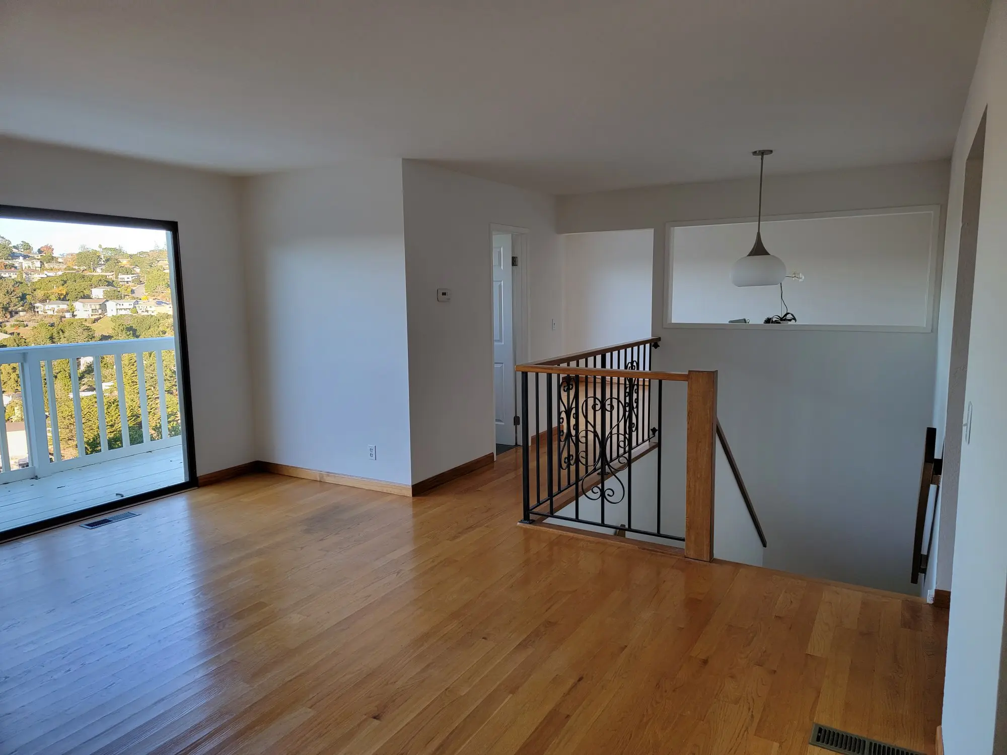 Empty room with wooden floor, white walls, and a staircase.