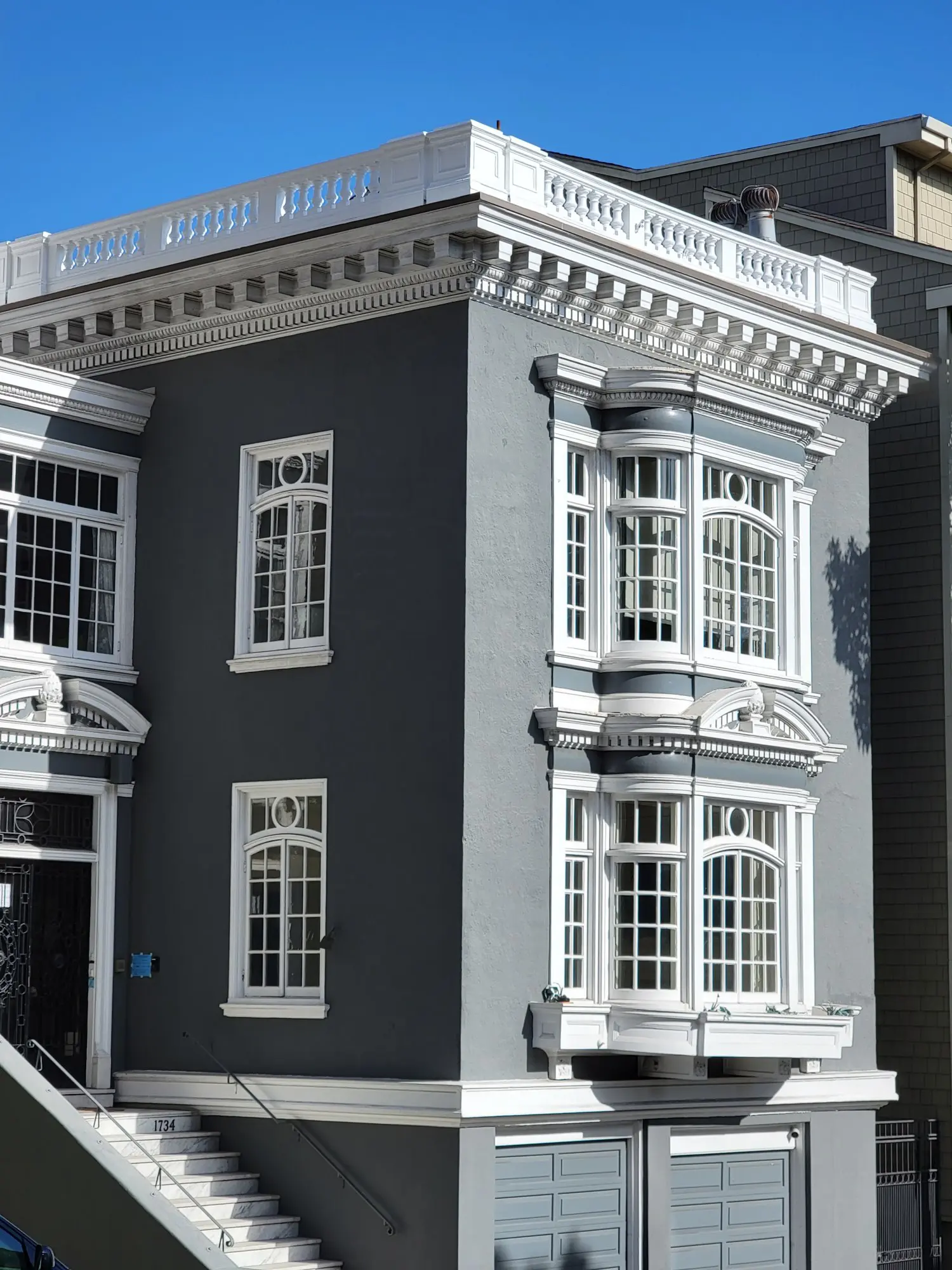 Elegant gray building with classic white-trimmed windows and detailed cornices.
