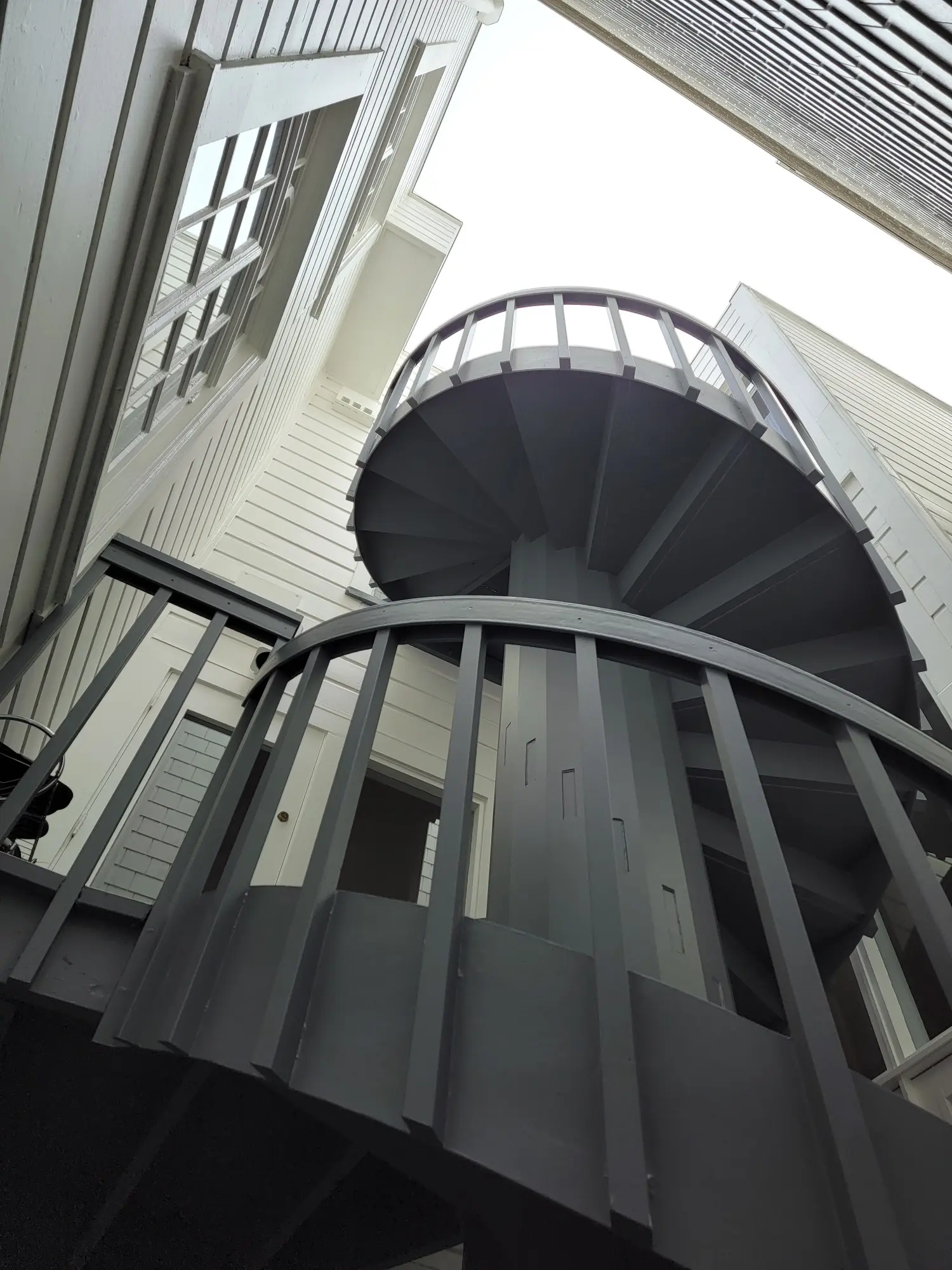 Upward view of a spiral staircase in an urban setting.