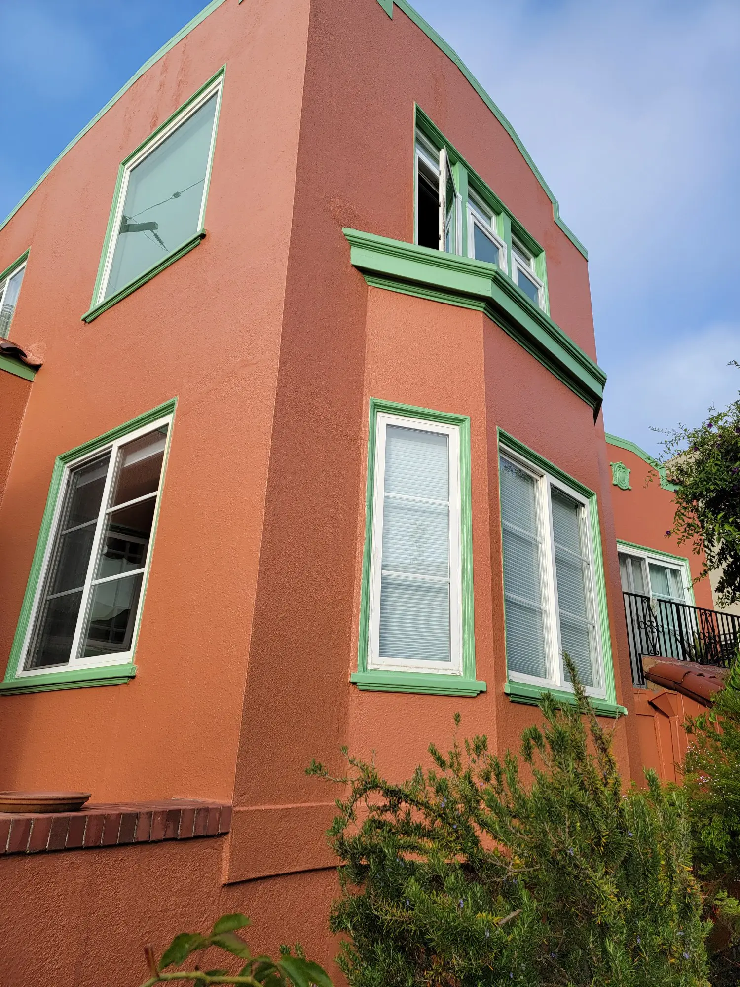 Exterior view of a coral-colored house corner with multiple windows.