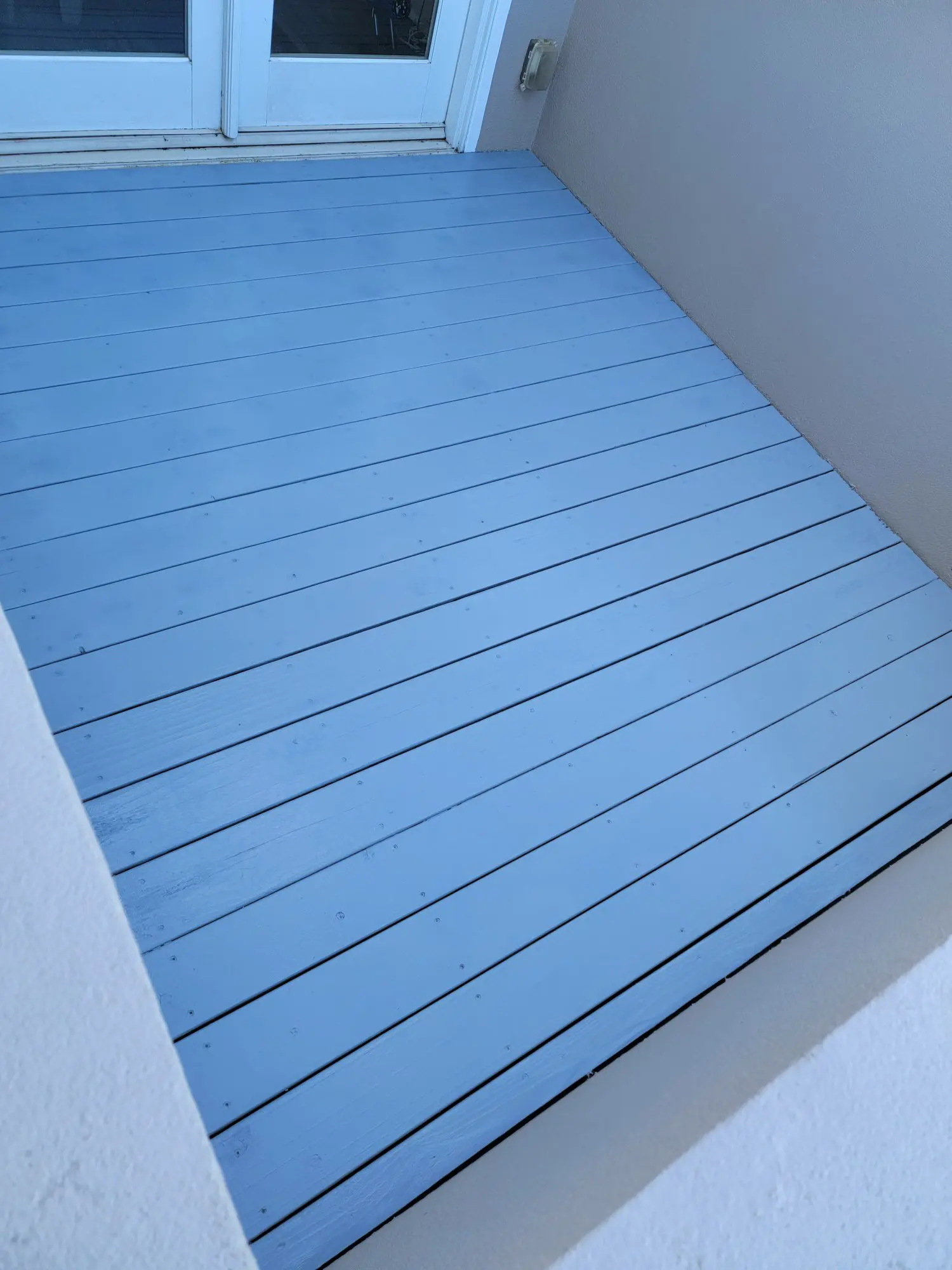 Blue wooden floor panels arranged neatly in an empty room corner.