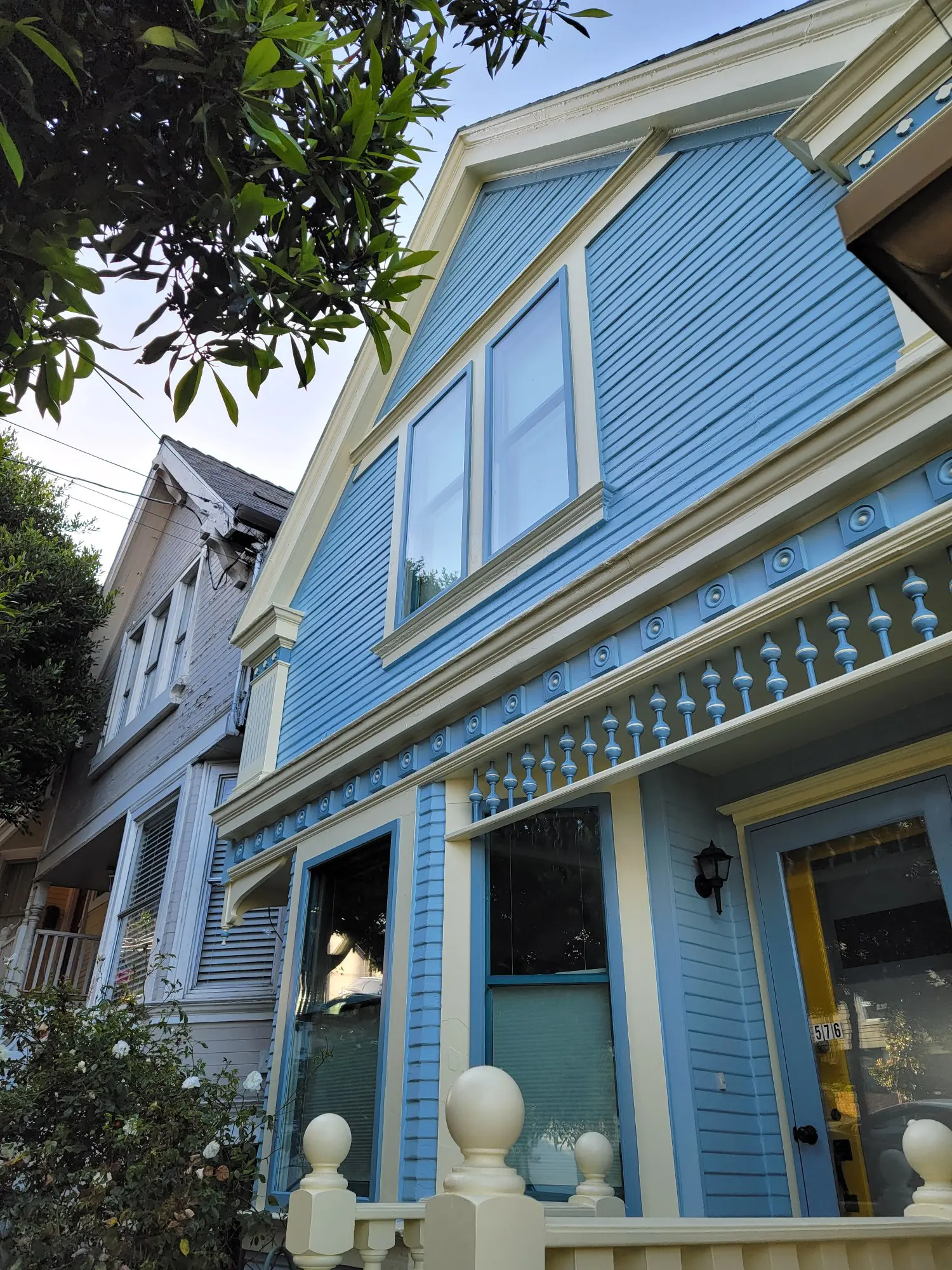 Blue Victorian-style house with decorative trim and large windows.
