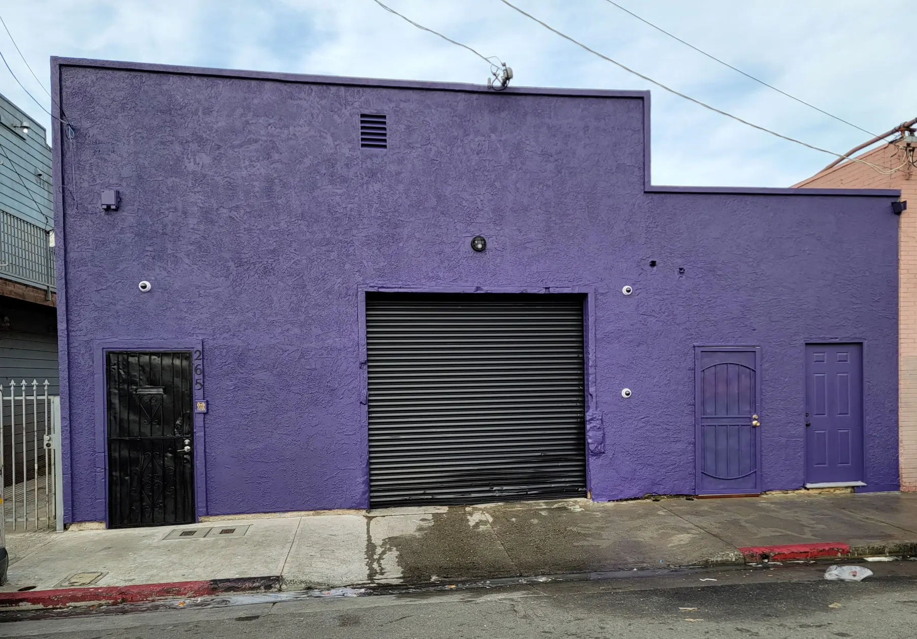 A purple building with a black garage door and small windows.
