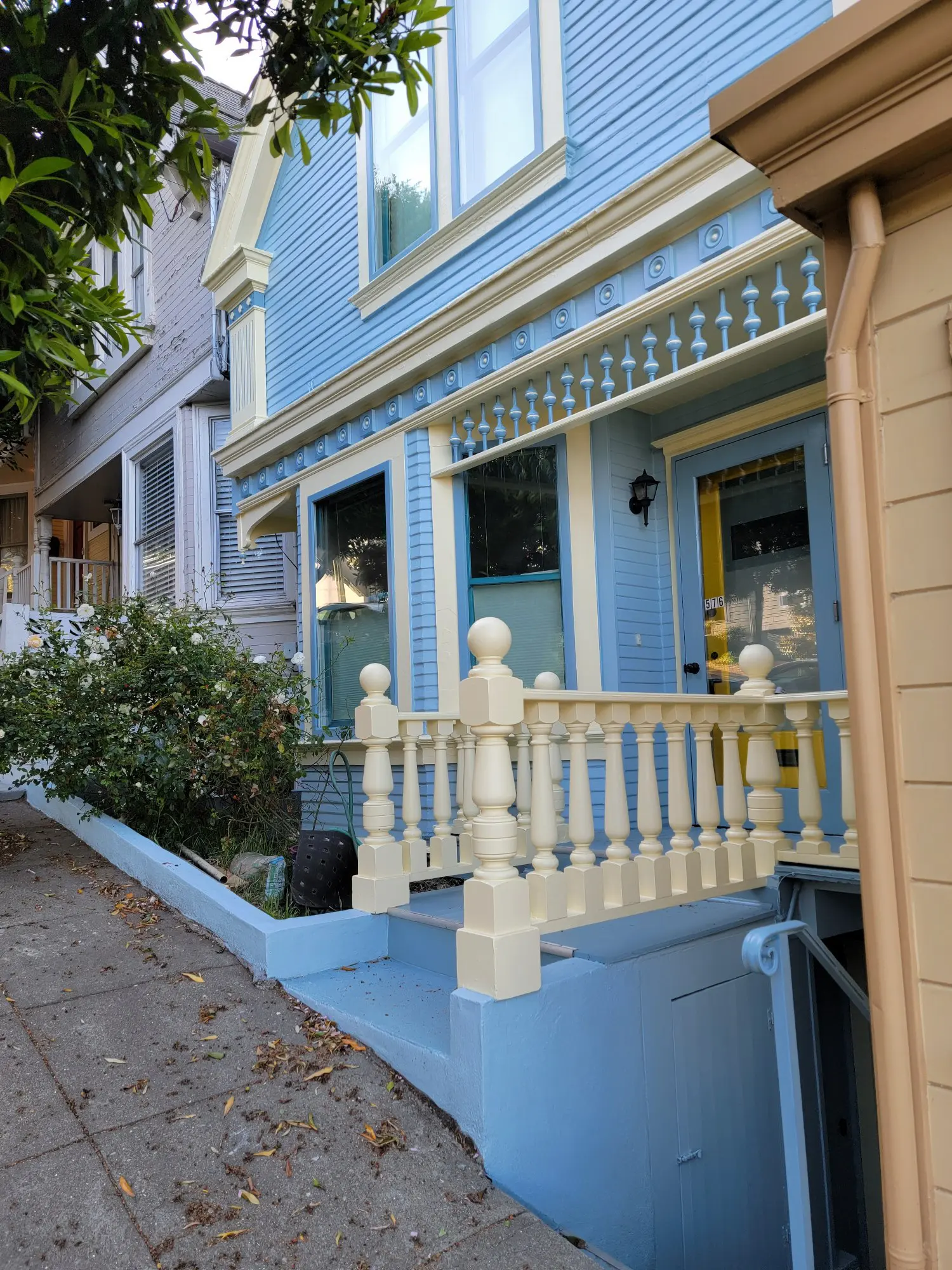 A charming blue house with a white porch railing on a quiet street.