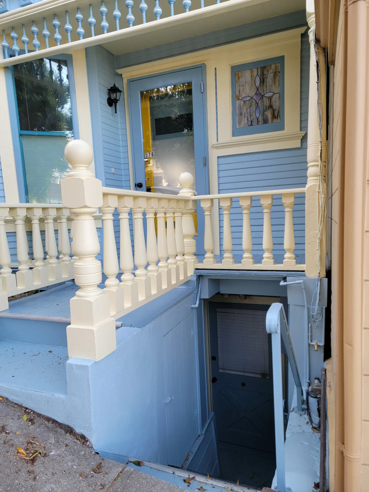 Blue and white porch with stairs and a basement door beneath.