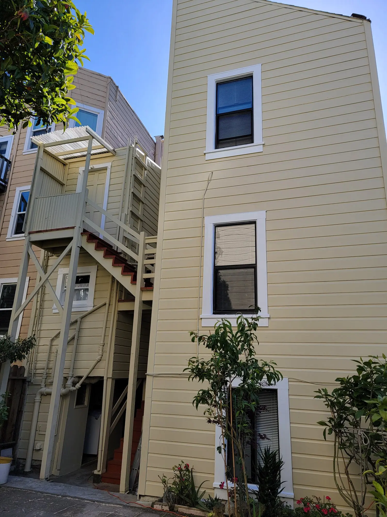 Exterior of a yellow building with an external staircase and windows.