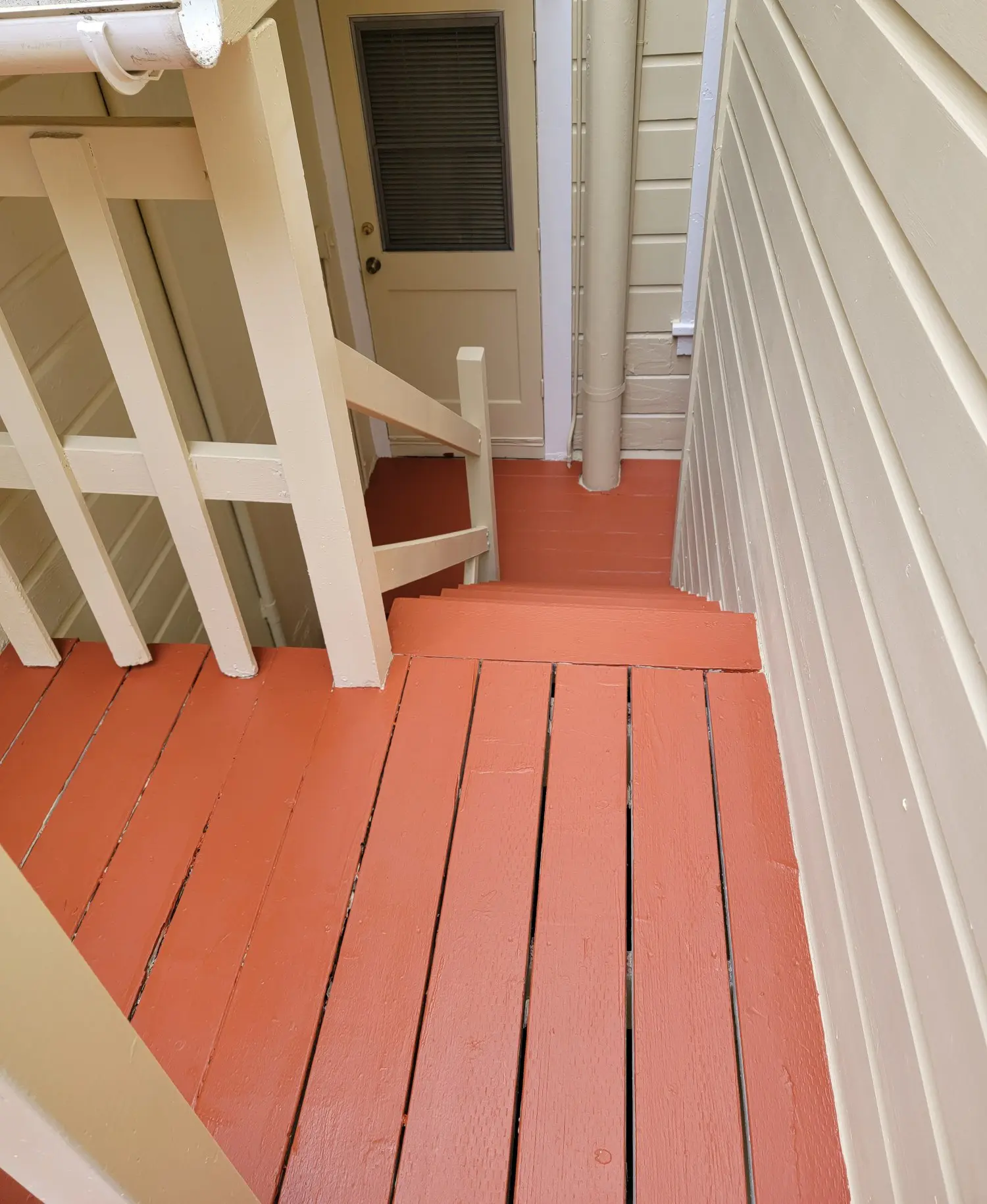 Wooden stairs and deck painted in terracotta and beige colors.