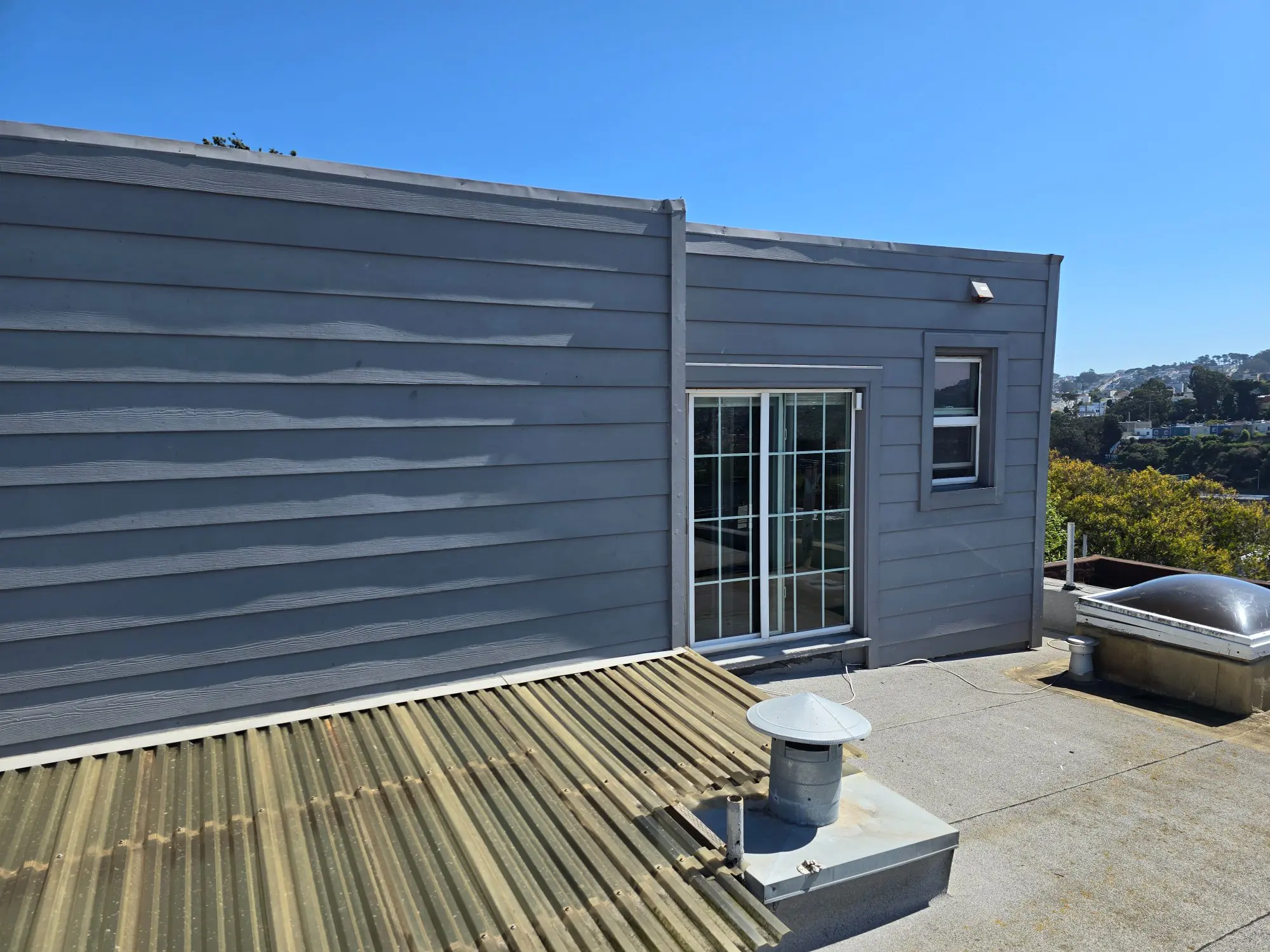 Modern rooftop with a blue building and sliding glass door.