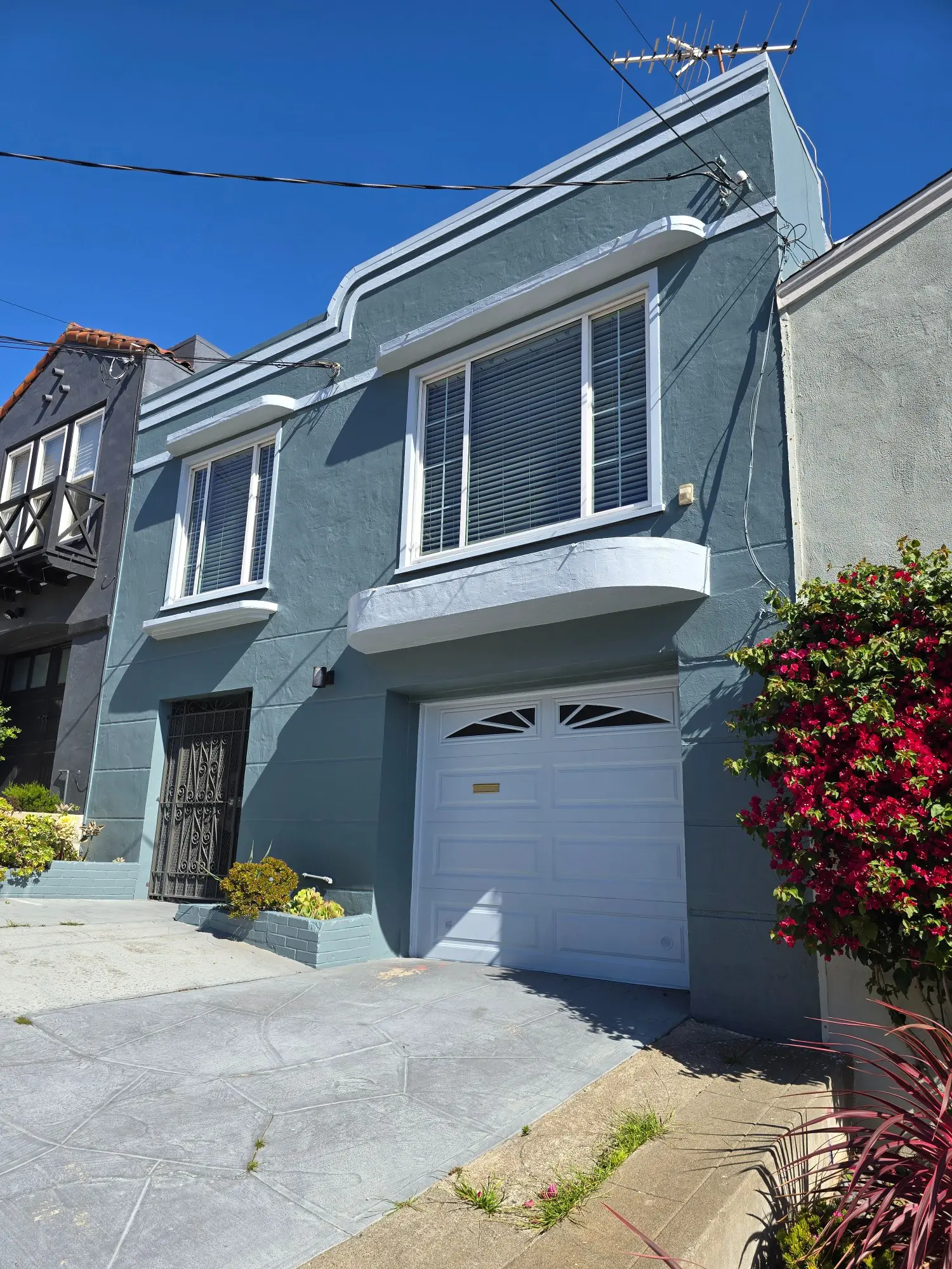 A blue house with garage and bay windows under a clear sky.