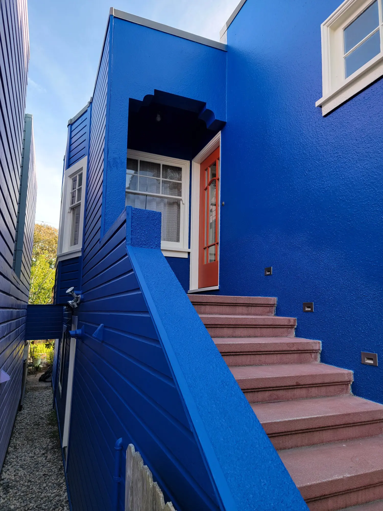 Blue exterior wall with stairs leading to an open door.