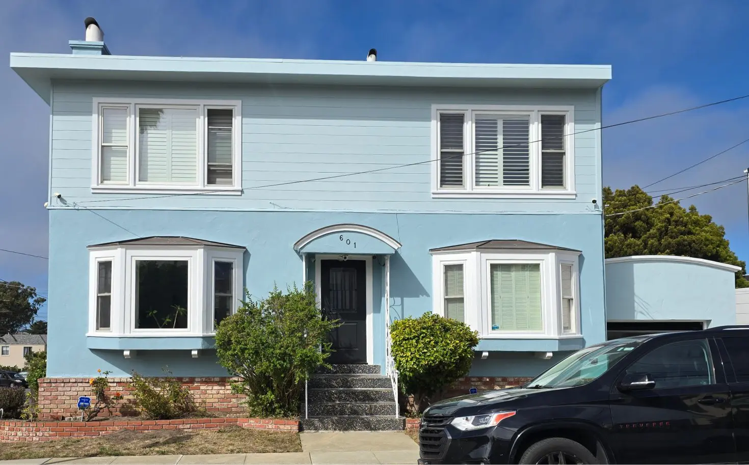 Light blue two-story house with white trim and front garden.