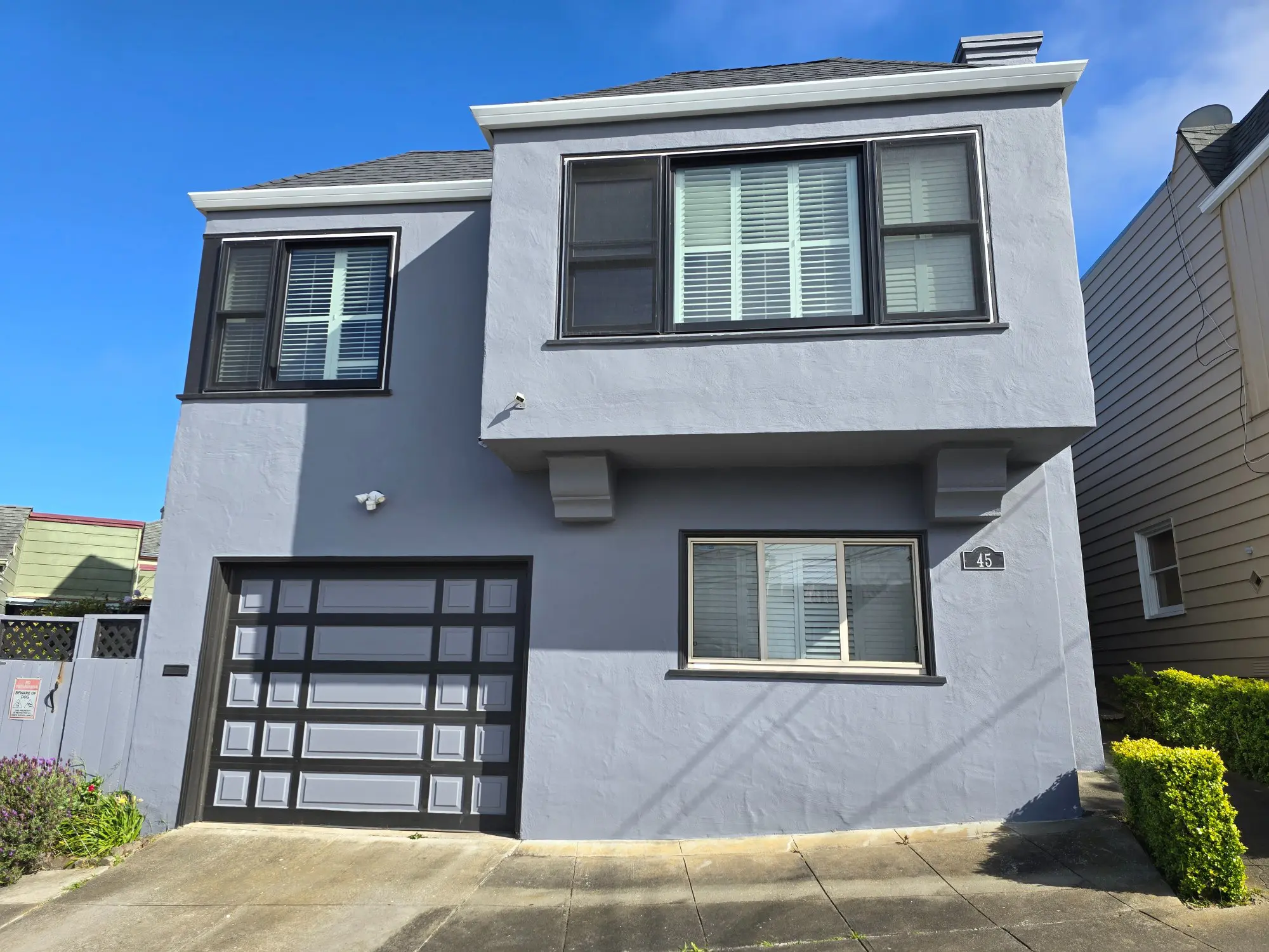 Two-story gray house with garage and windows on a sunny day.