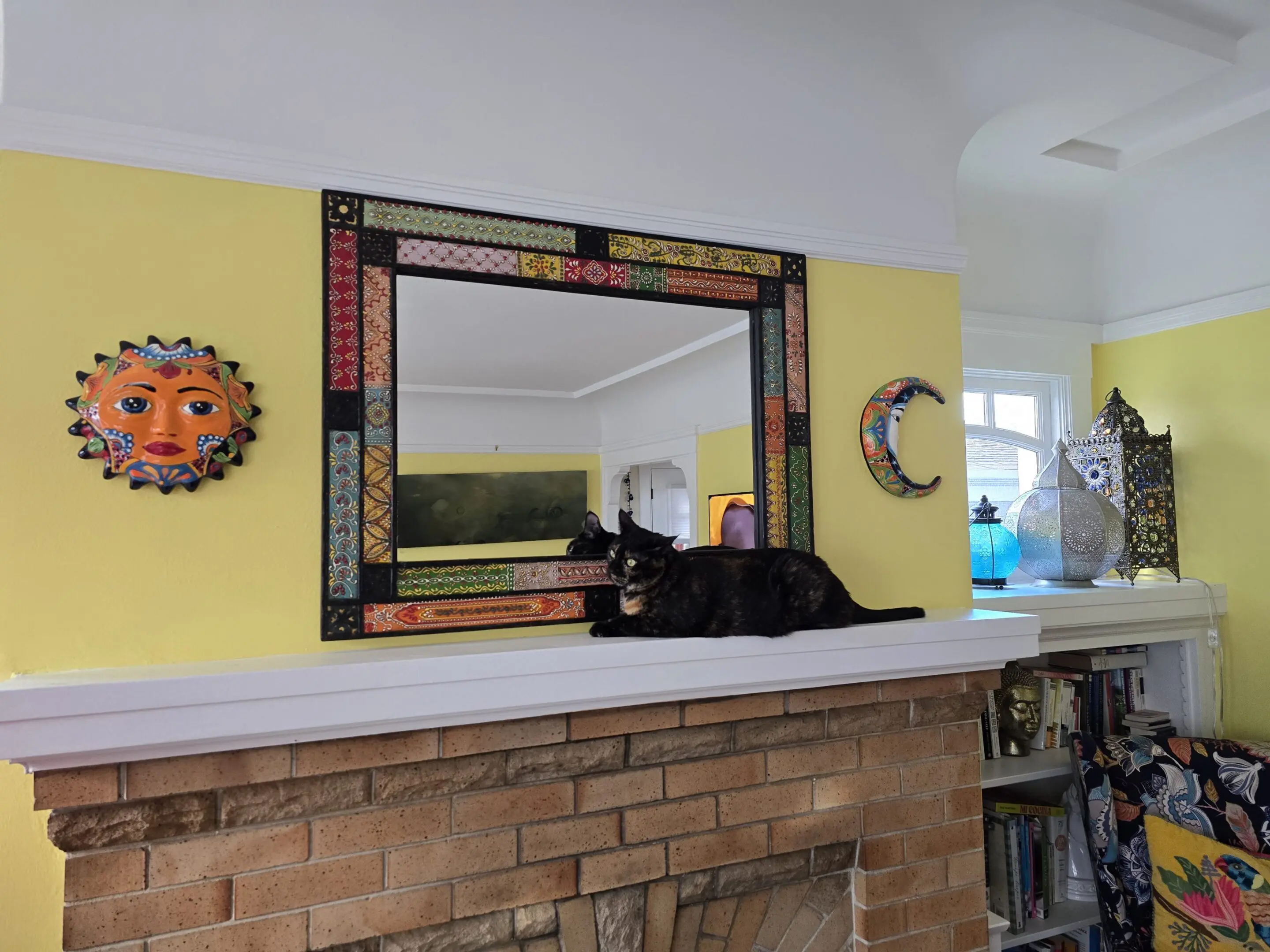 Decorative mirror above fireplace with sun and moon wall art.