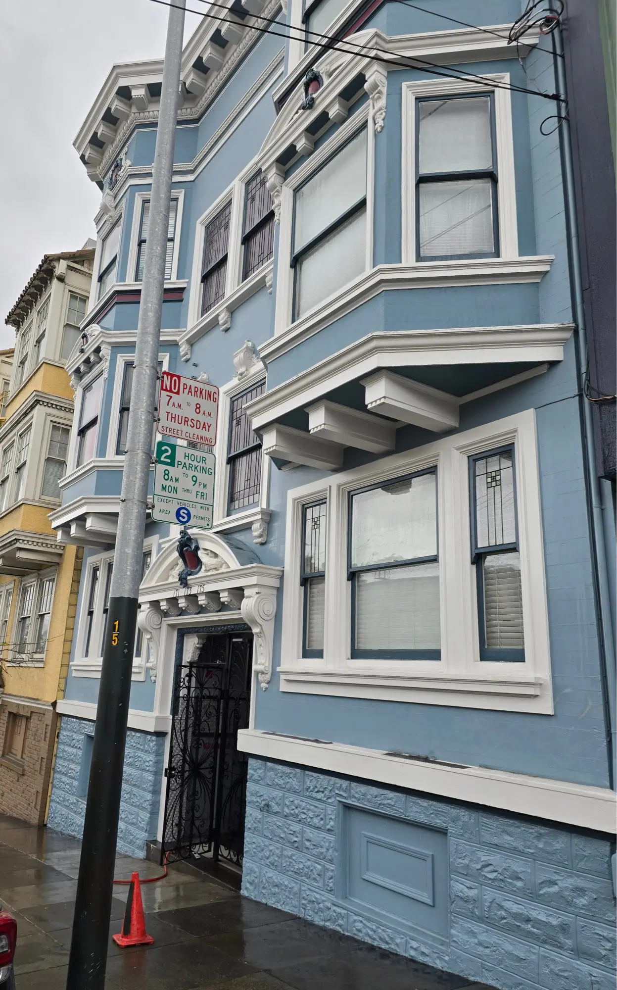 Blue Victorian-style house with bay windows and ornate architectural details.