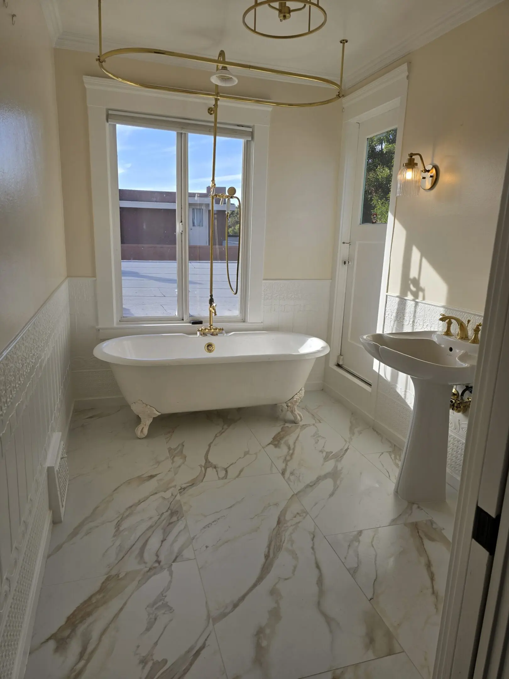 Bright bathroom with a freestanding bathtub and marble flooring.