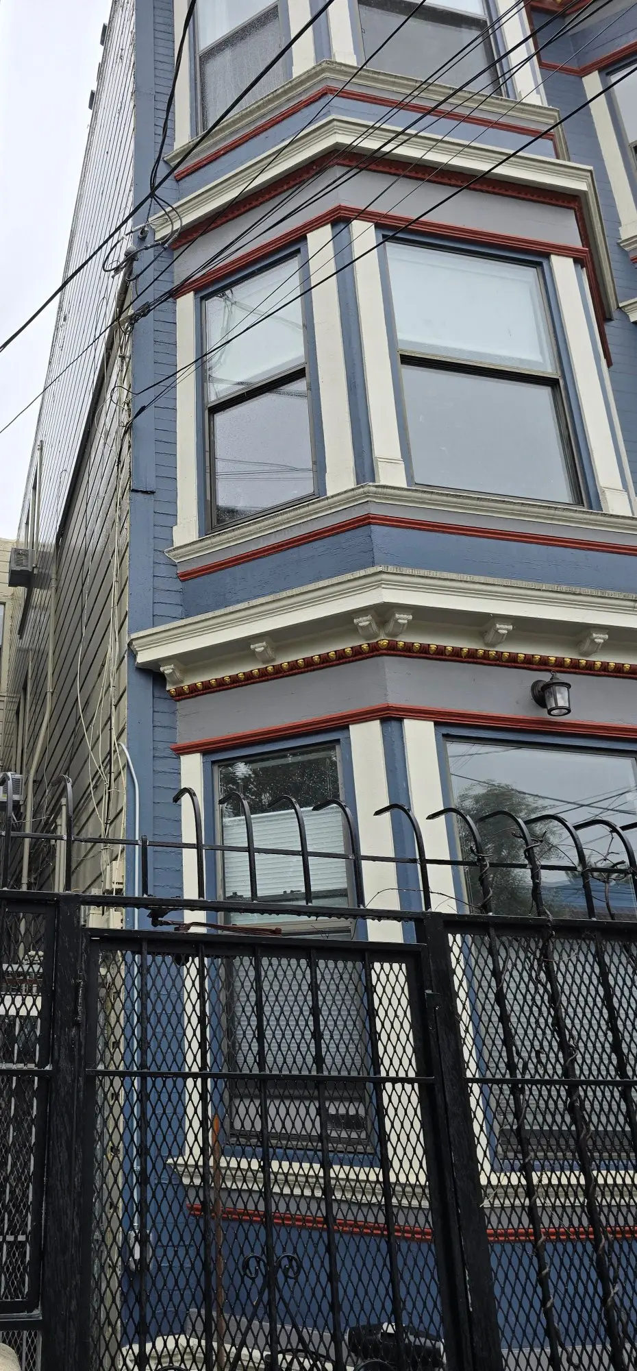 Blue and gray Victorian-style house with detailed trim and a black fence.