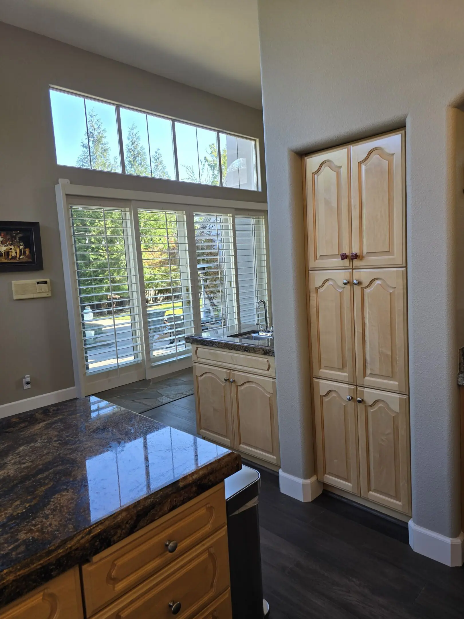 Bright kitchen with large windows and wooden cabinets.