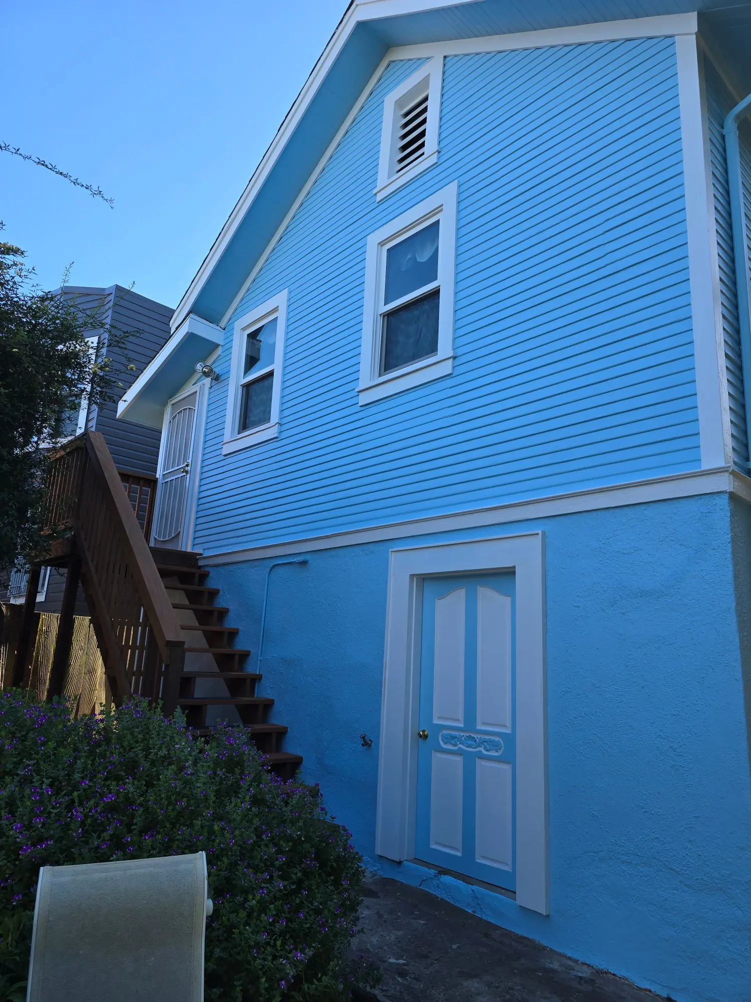 Blue two-story house with wooden stairs and white-trimmed windows.