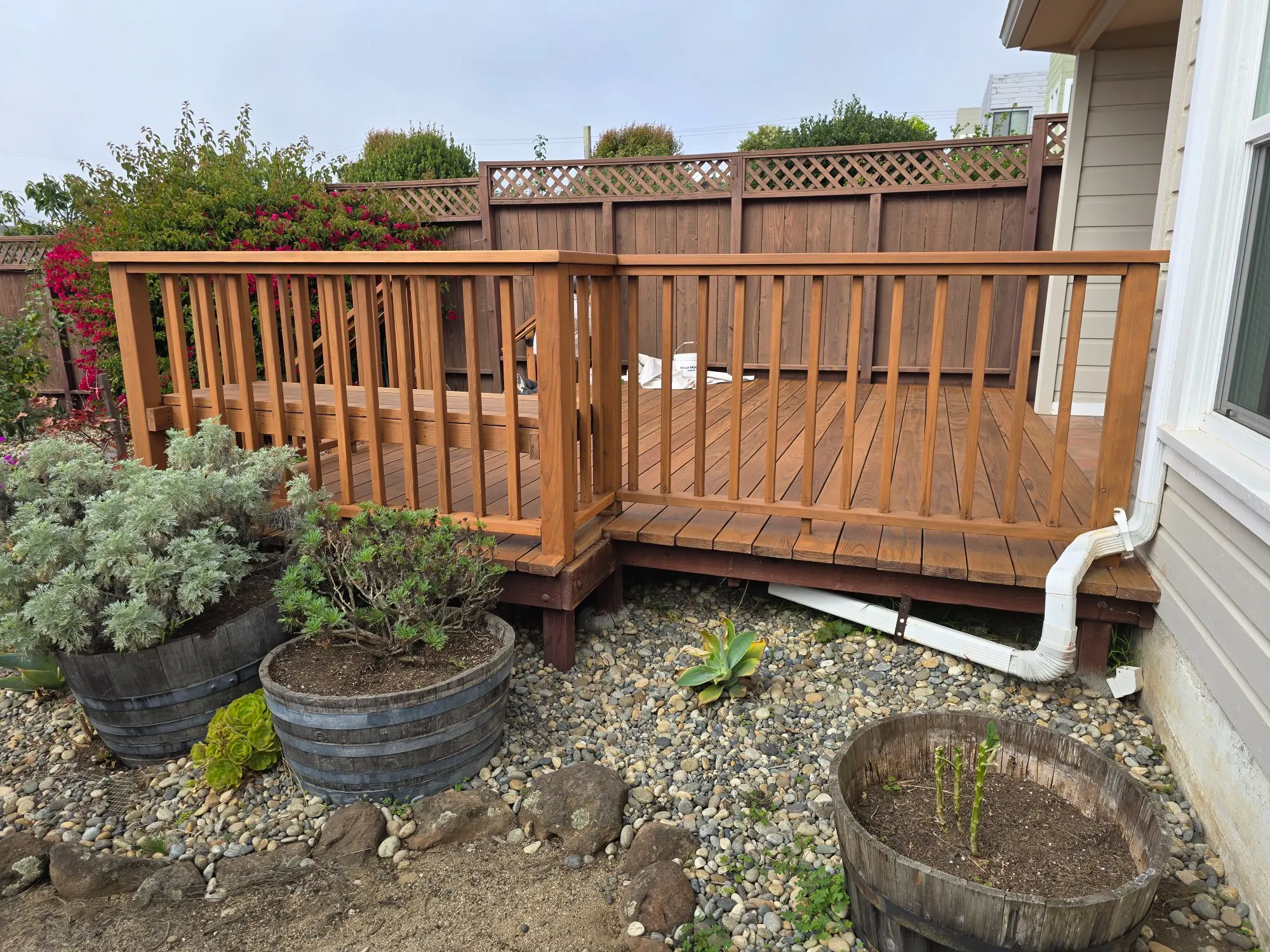 Wooden deck with garden planters and a fence in the background.