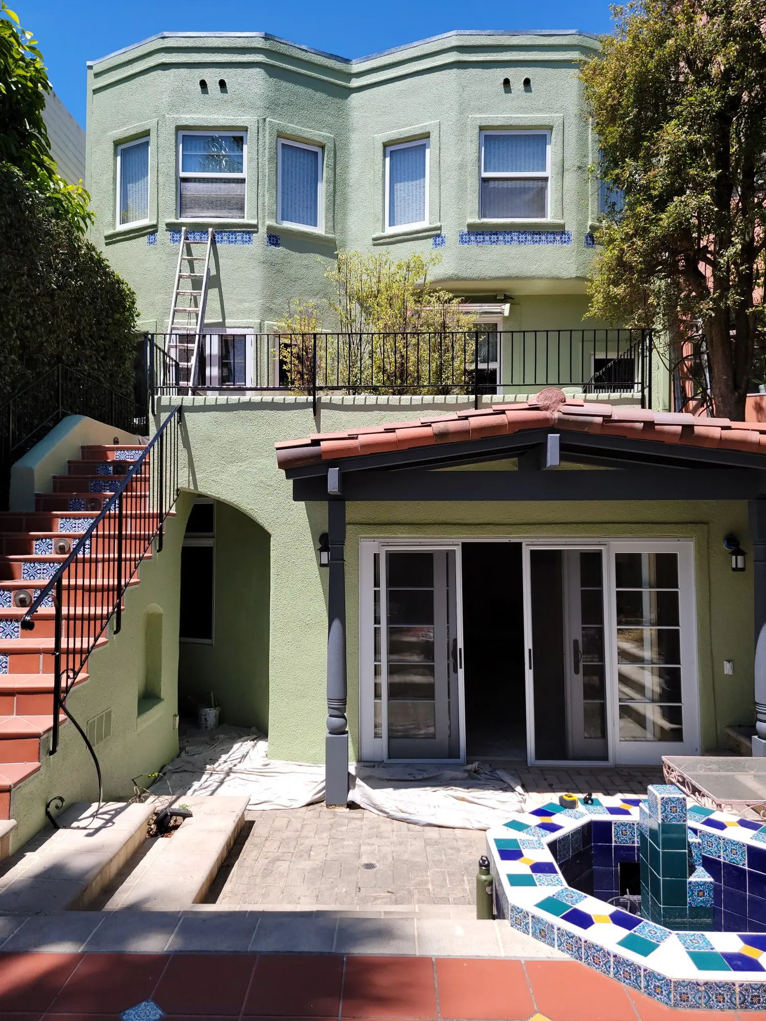 Backyard with stairs leading to a patio and a small building with glass doors.