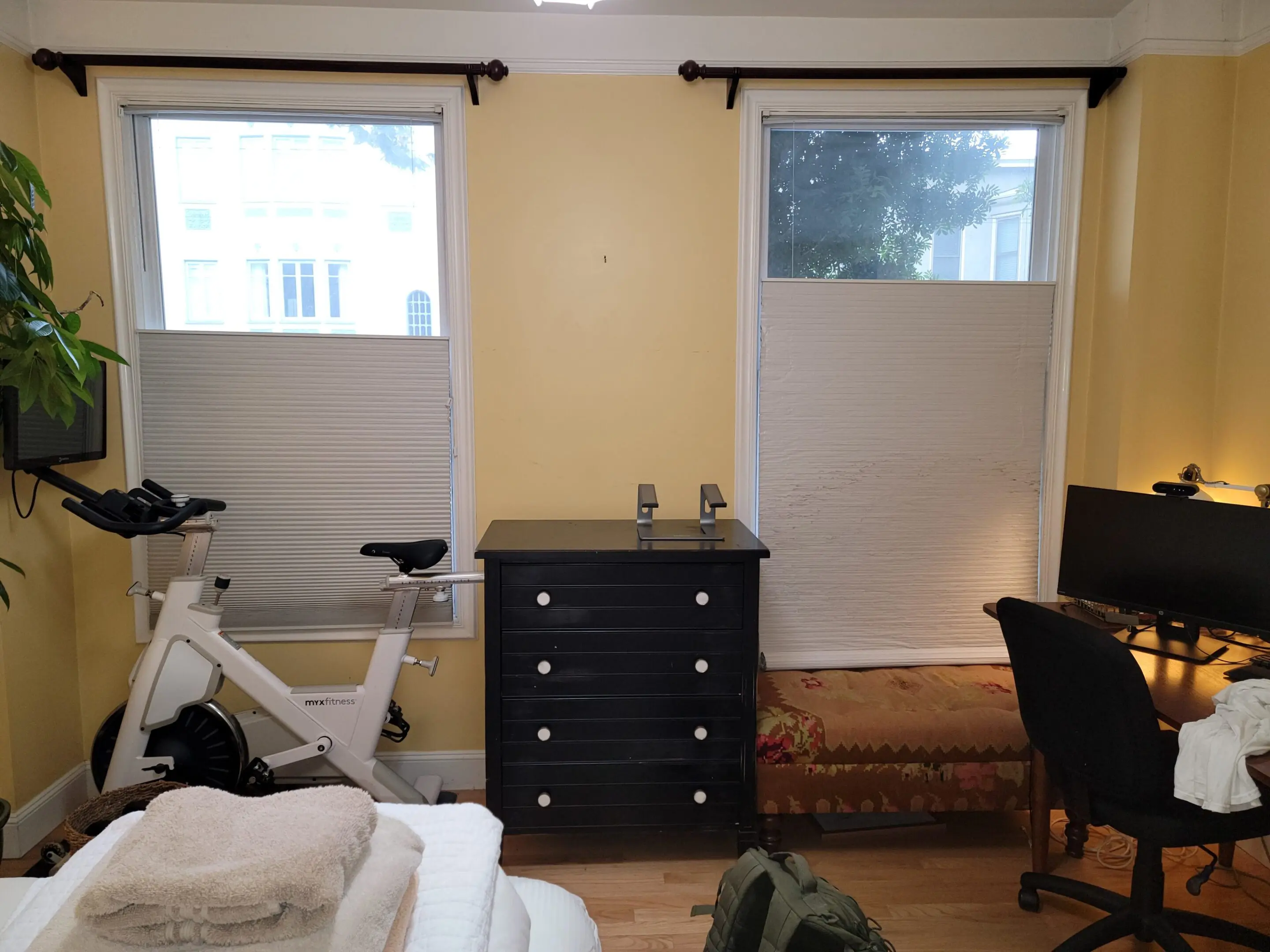 Cozy room with white curtains, a black dresser, and a bicycle by the window.