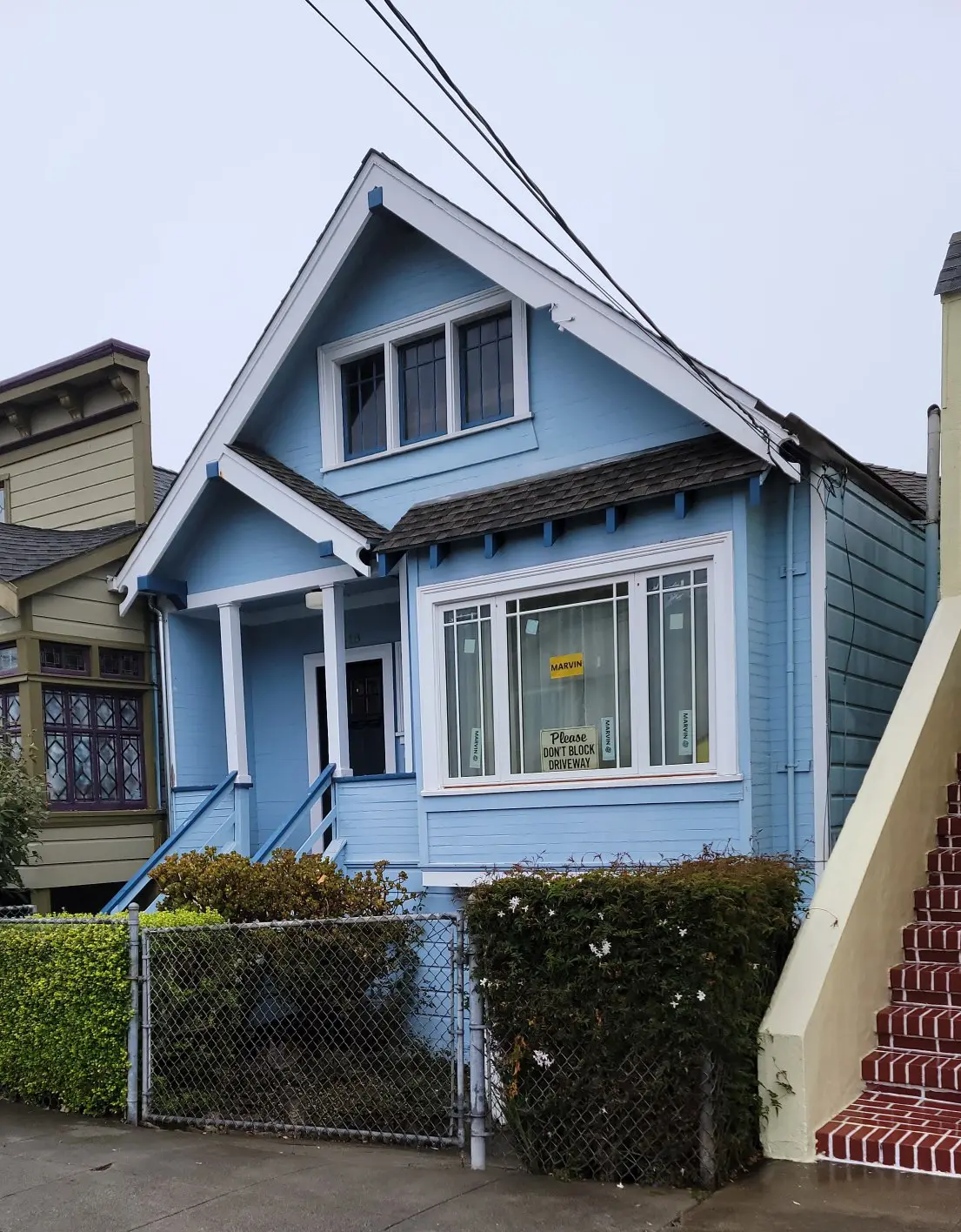 A quaint blue house with a steep roof and white trim.