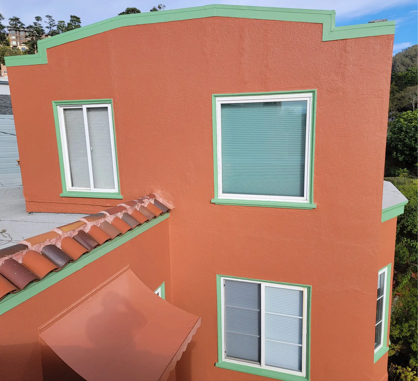 Orange building with white-trimmed windows and tiled roof section.