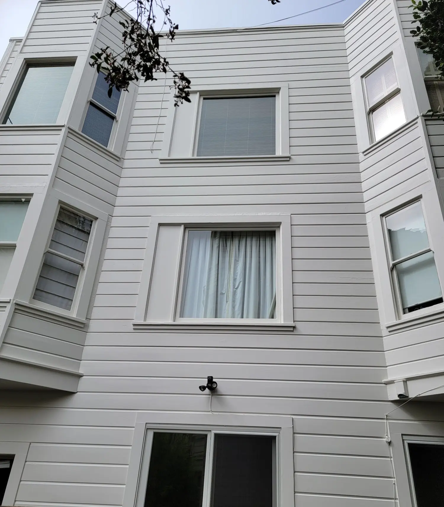 White multi-story building with rectangular windows and vertical siding.