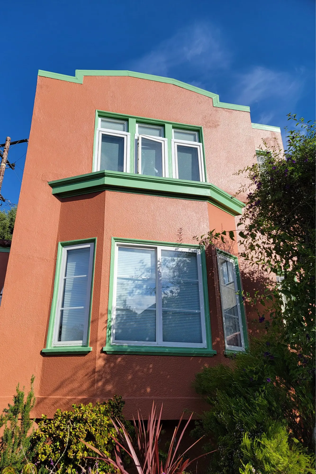 Colorful two-story house with large windows and green trim.