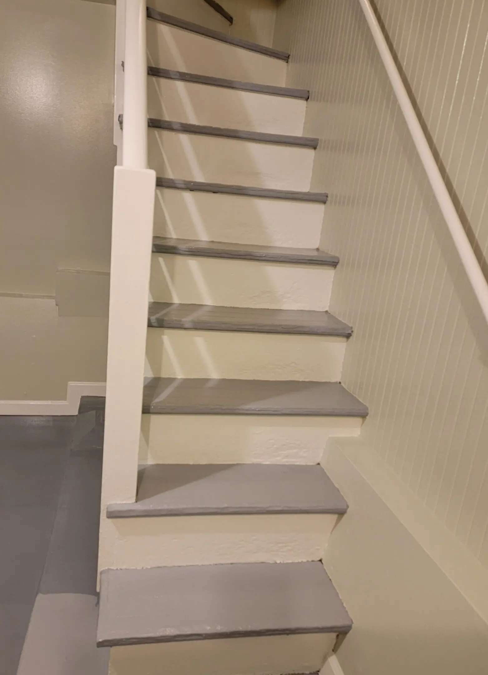A narrow staircase with a half wall on one side and a handrail on the other.