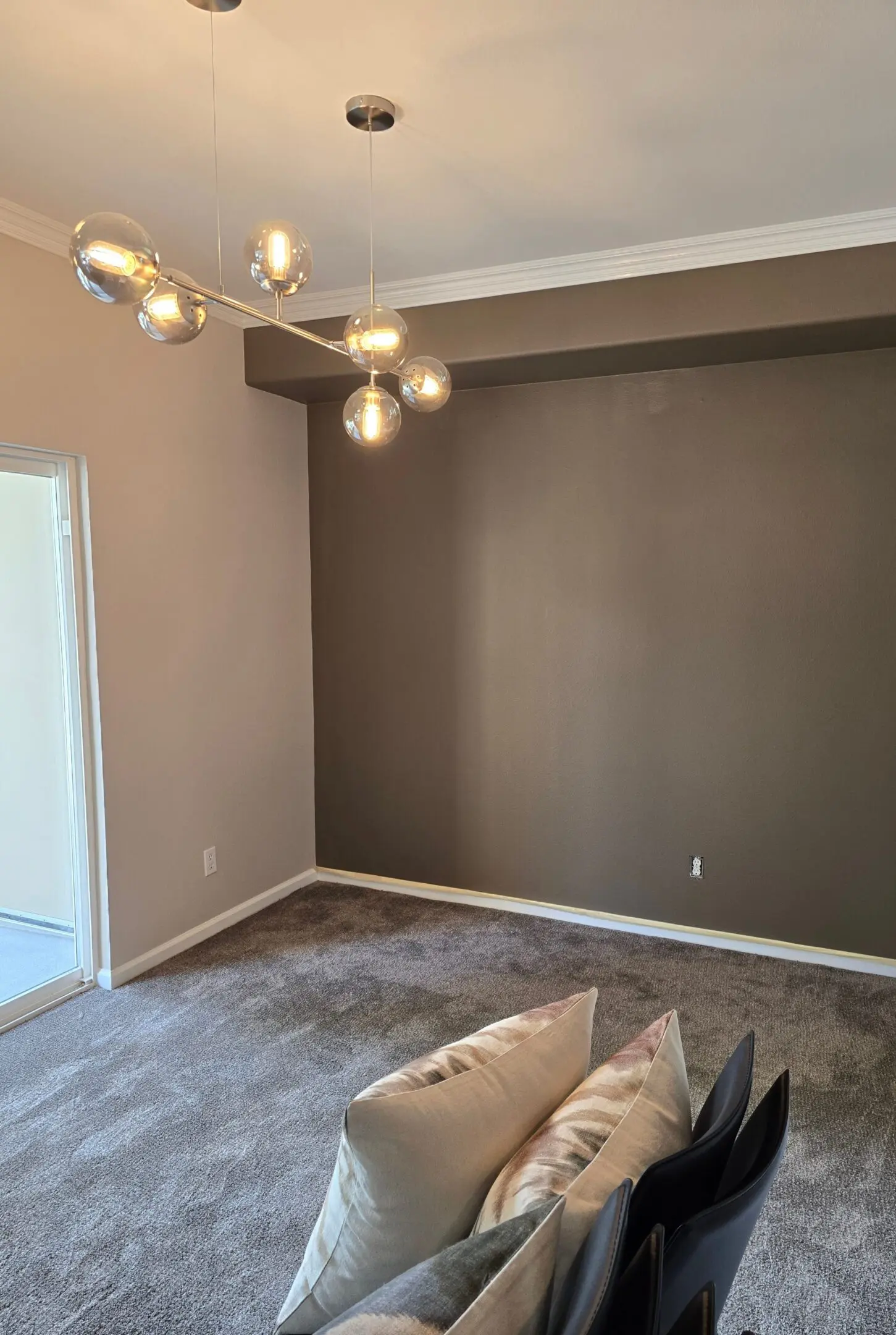 Modern empty room with gray accent wall and carpet flooring.