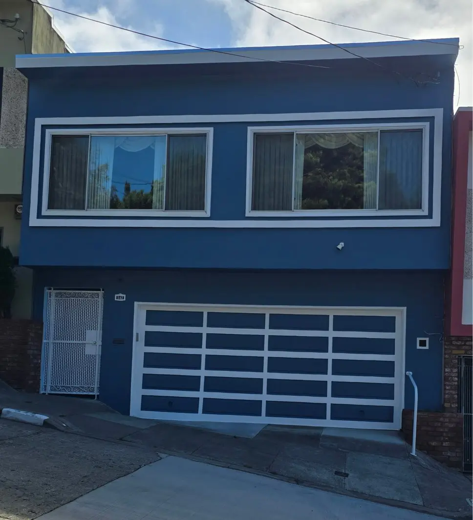 Blue two-story house with large garage doors and windows.