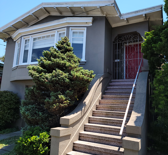 Exterior view of a house with stairs and greenery.