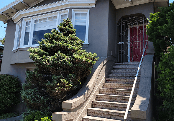 Exterior view of a house with stairs and greenery.